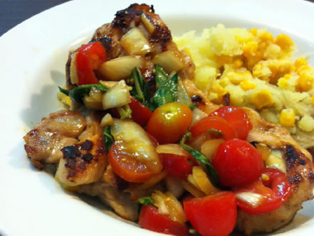 Frango com molho para salada de tomate picado e manjericão e batata com milho